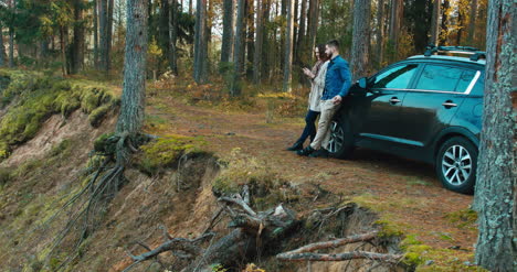 Couple-leaning-against-car-admire-forest-view-4K